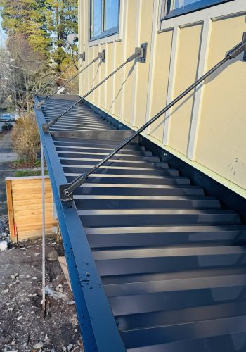 Custom-built black metal awning installed on a modern residential building in Seattle with angled steel support rods.