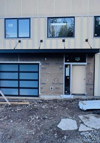 Modern multi-unit home under construction featuring a black metal awning above the garage and entry doors. CUSTOM IRON WORKS
