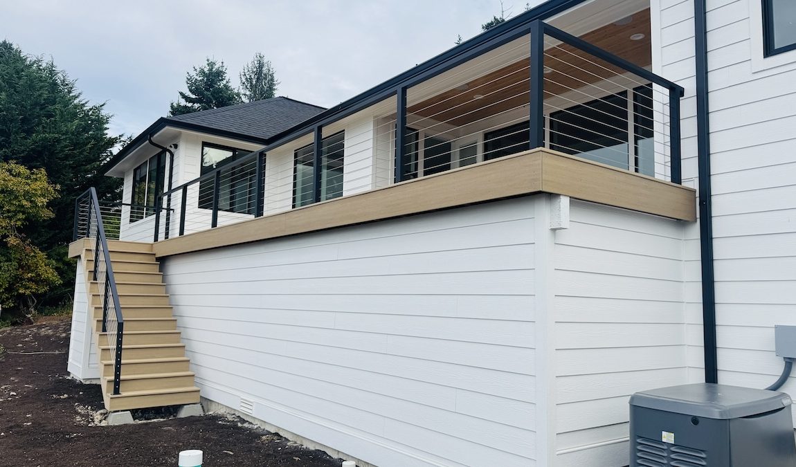 Modern elevated deck in Seattle with black metal cable railing and wood stairs, featuring custom iron works on a contemporary home exterior.